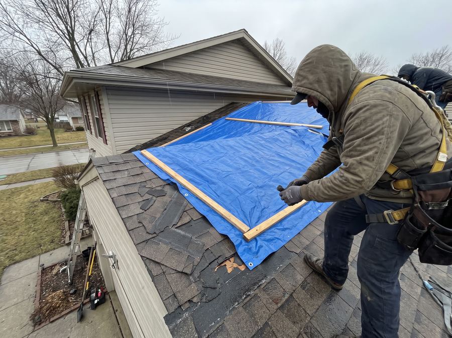 Emergency tarp covering storm-damaged roof section