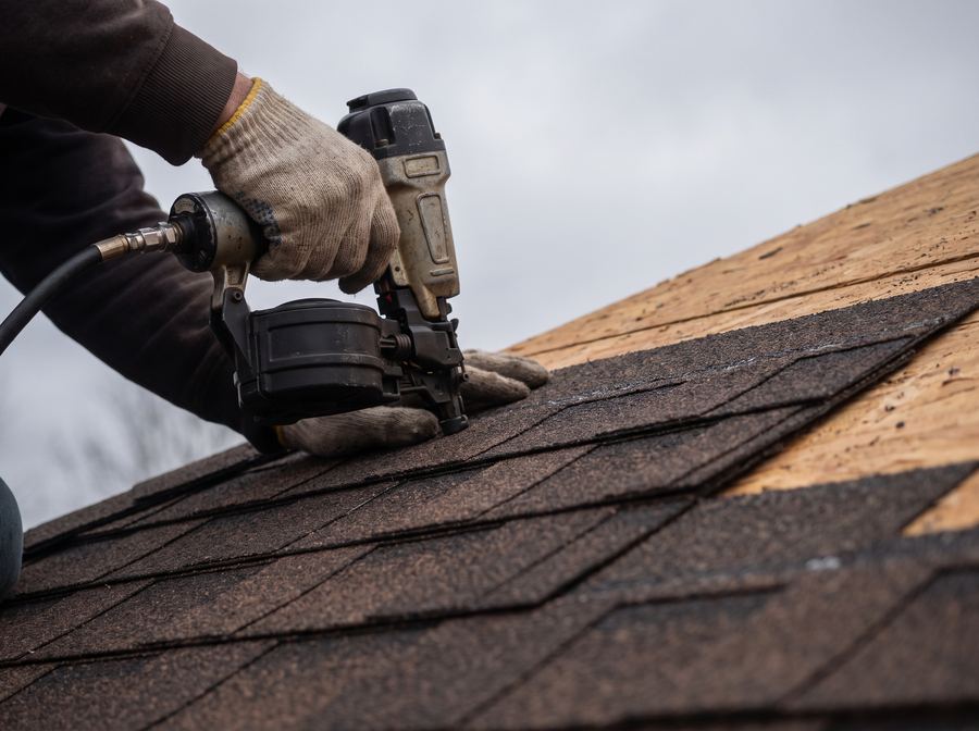 Roofer installing new architectural shingles during a roof replacement in Peoria, IL
